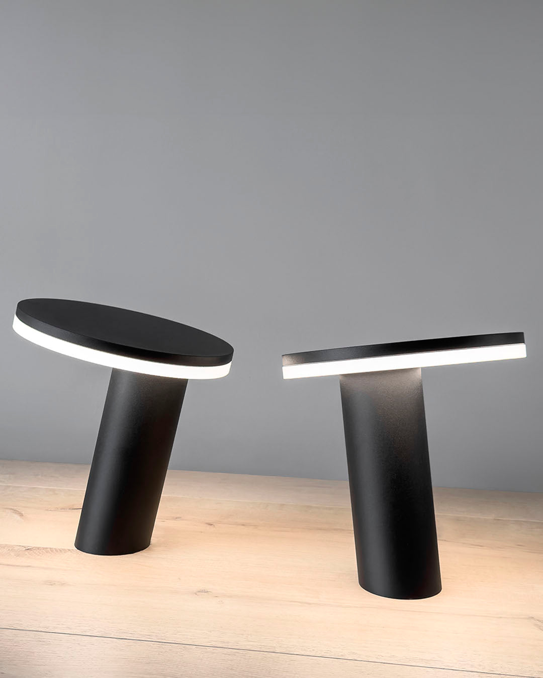 Lámparas de mesa modernas negras con luz LED sobre superficie de madera clara