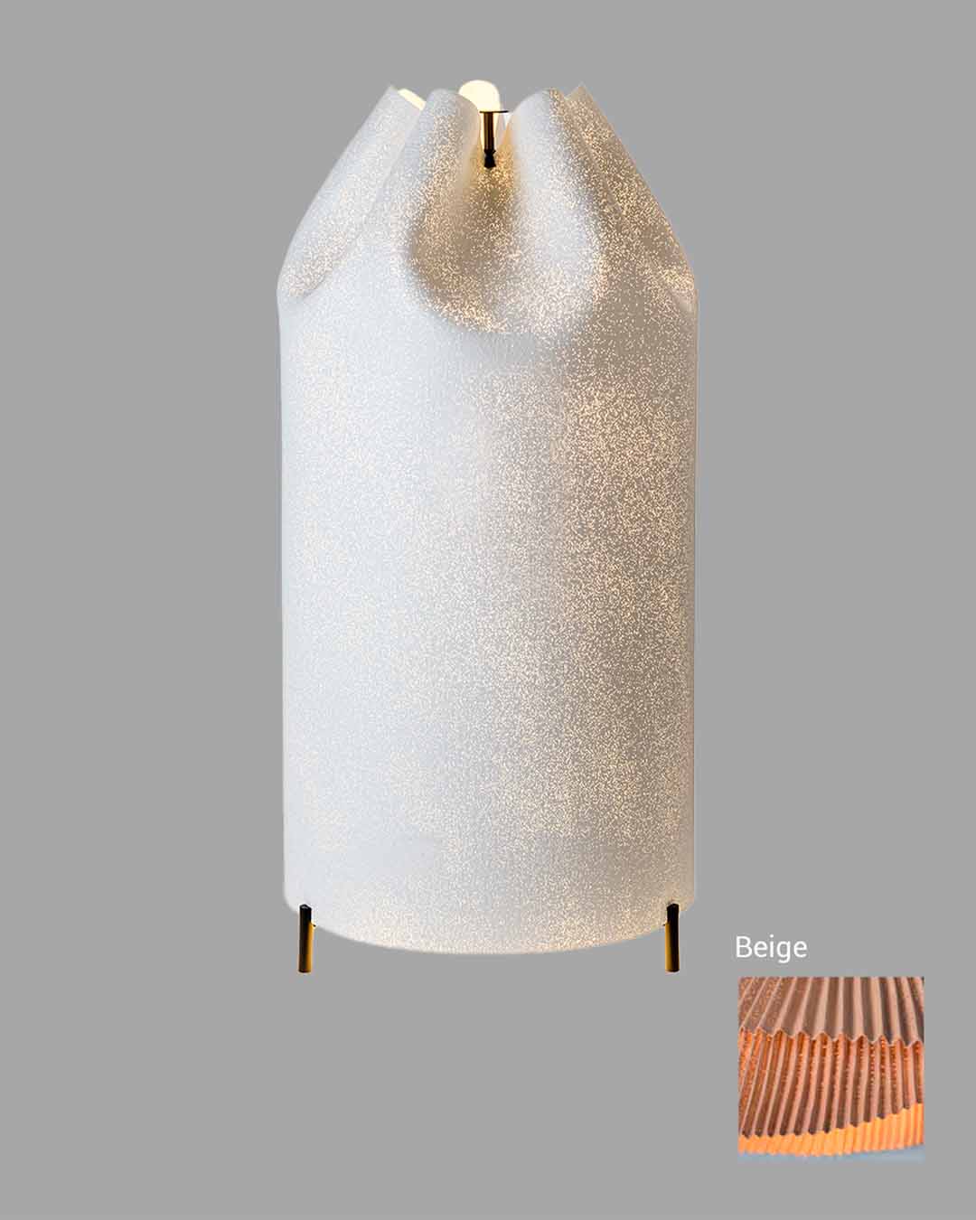 Lámpara de mesa moderna color beige con pantalla plisada y base metálica dorada, fondo gris.