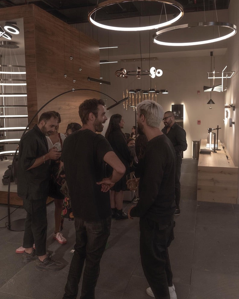 Personas conversando en una boutique de iluminación moderna con lámparas de diseño colgantes.