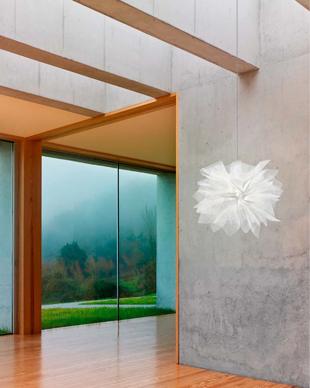 Lámpara colgante blanca de diseño moderno en sala minimalista con ventanales grandes