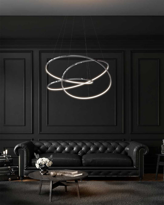 Lámpara colgante moderna de aros LED sobre sofá de piel negro en sala elegante.