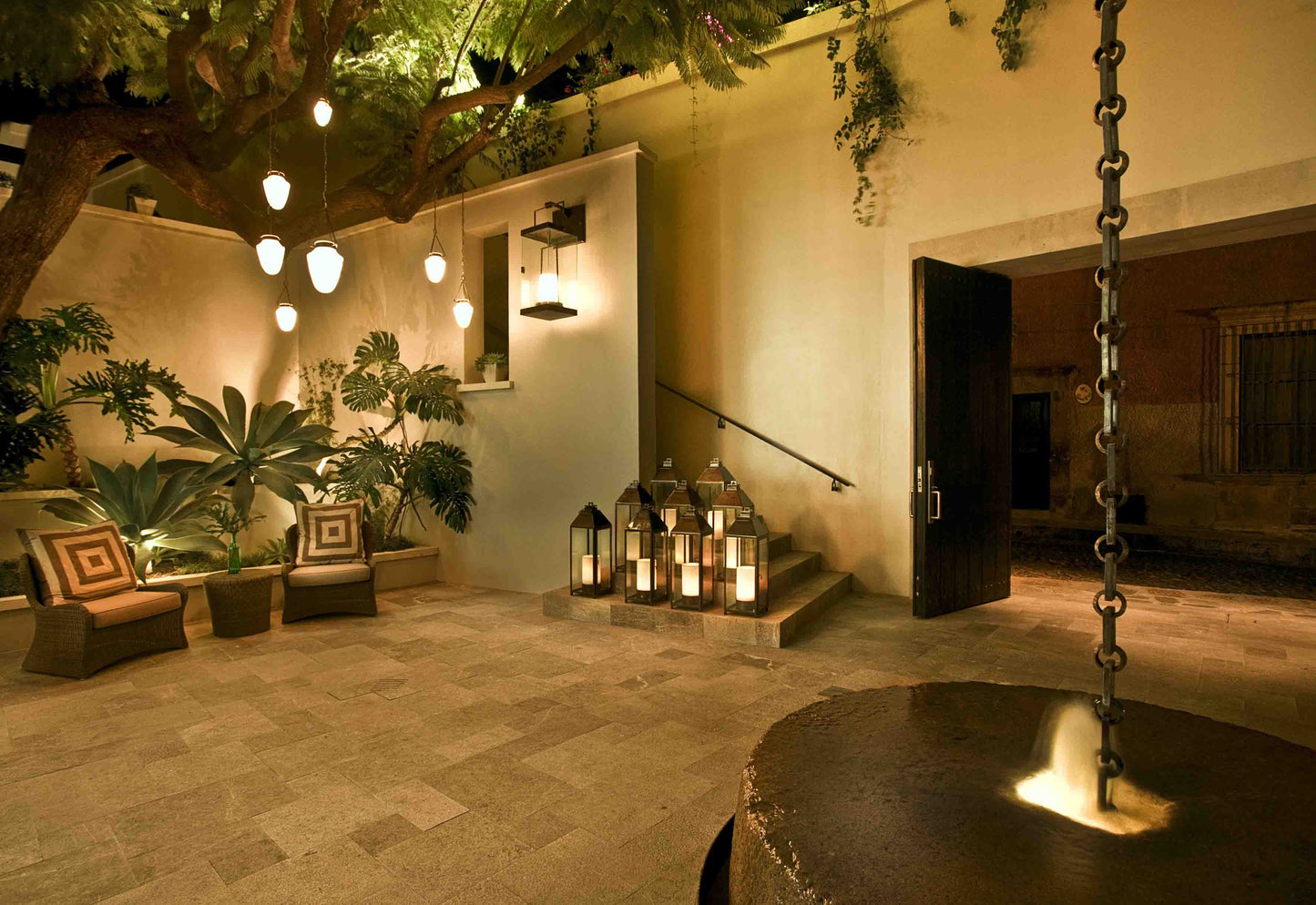 Entrada elegante con faroles, lámparas colgantes modernas y área de jardín iluminado