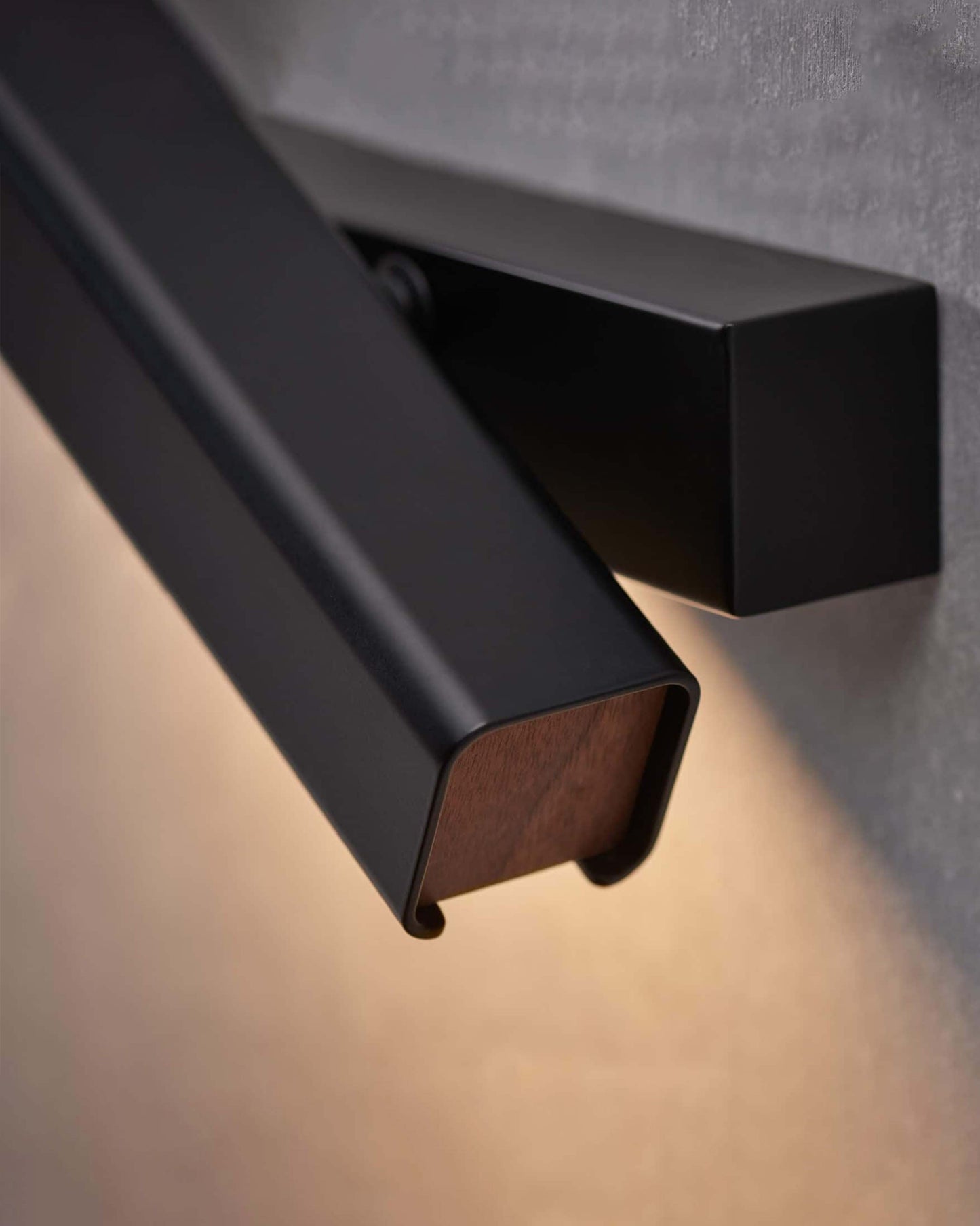Aplique de pared moderno de metal negro con detalles en madera y luz cálida decorativa.