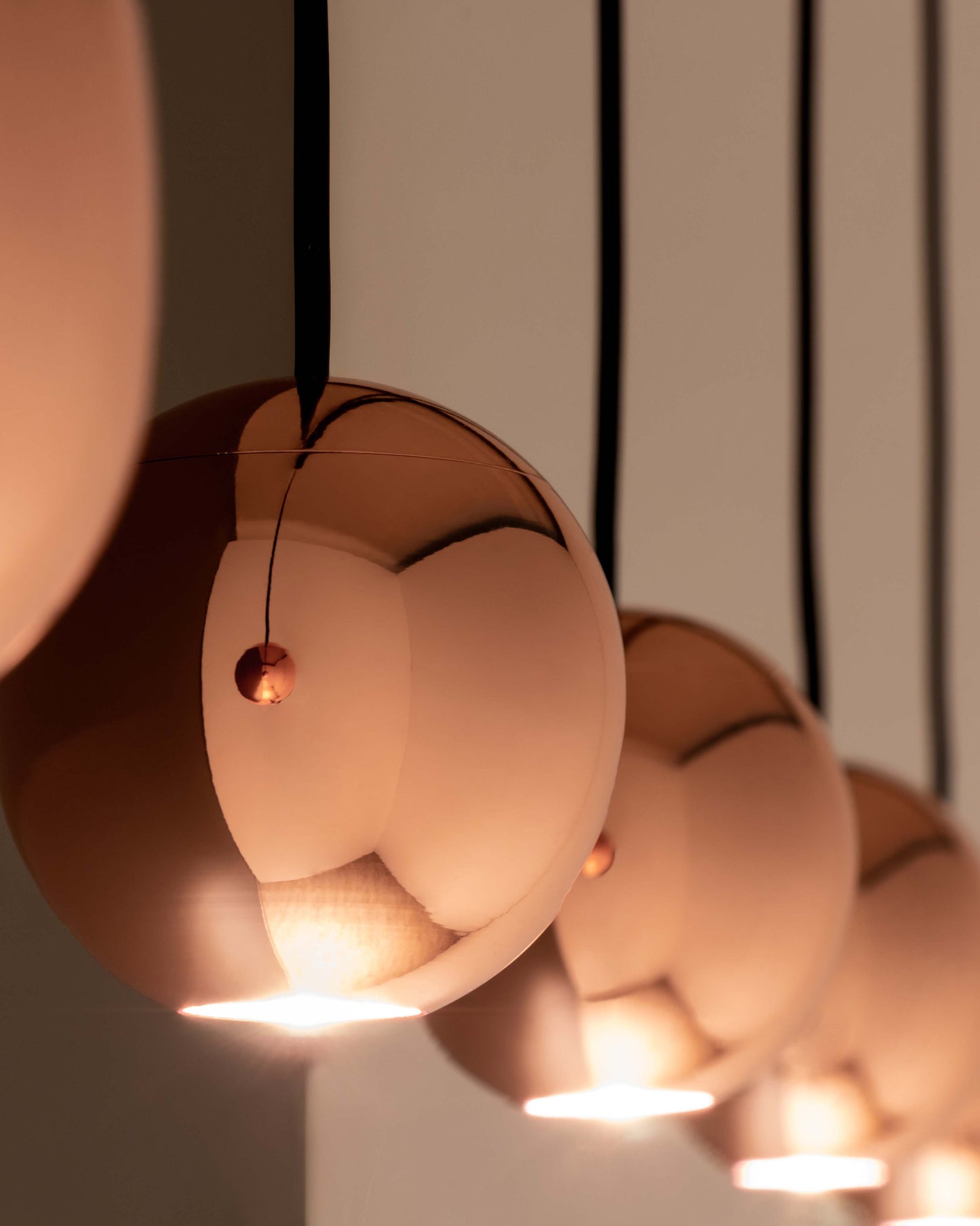 Lámparas colgantes esféricas color cobre encendidas, diseño moderno de iluminación interior.
