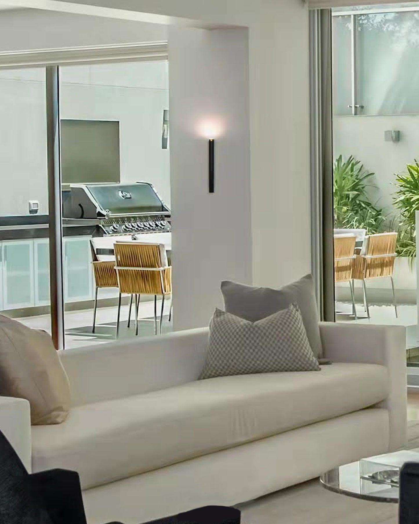 Aplique de pared moderno negro iluminando sala contemporánea con sofá y terraza exterior