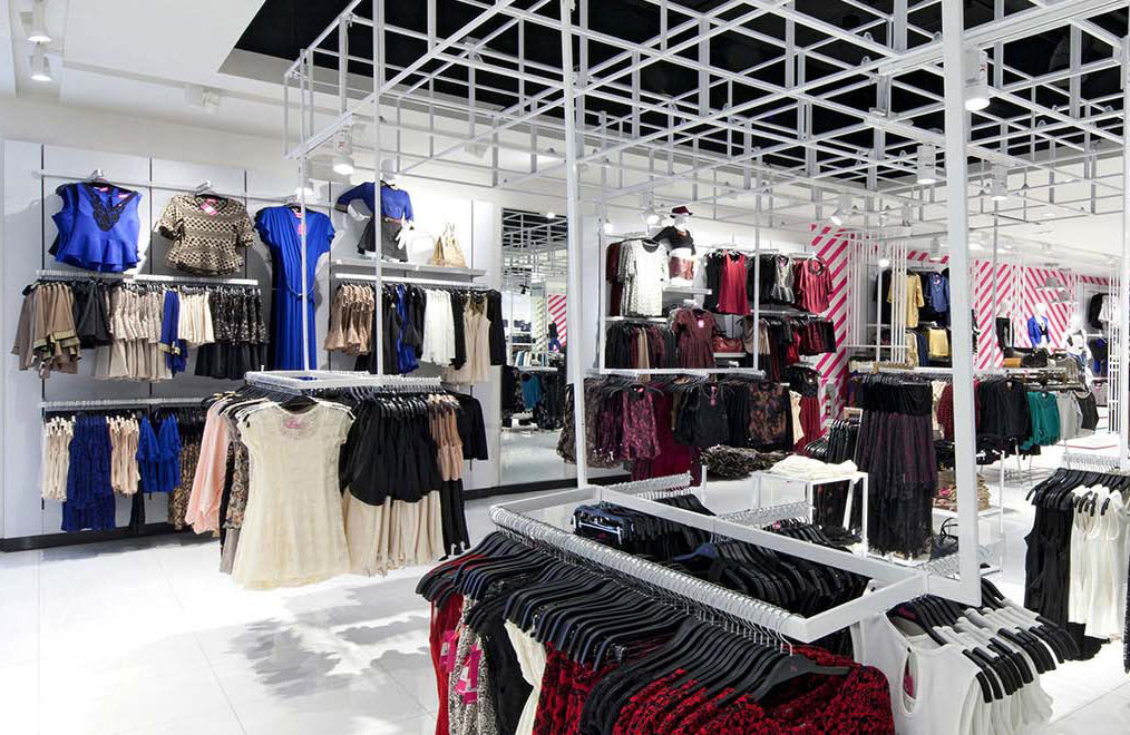 Tienda de ropa moderna con vestidos, blusas y faldas de mujer en exhibidores organizados