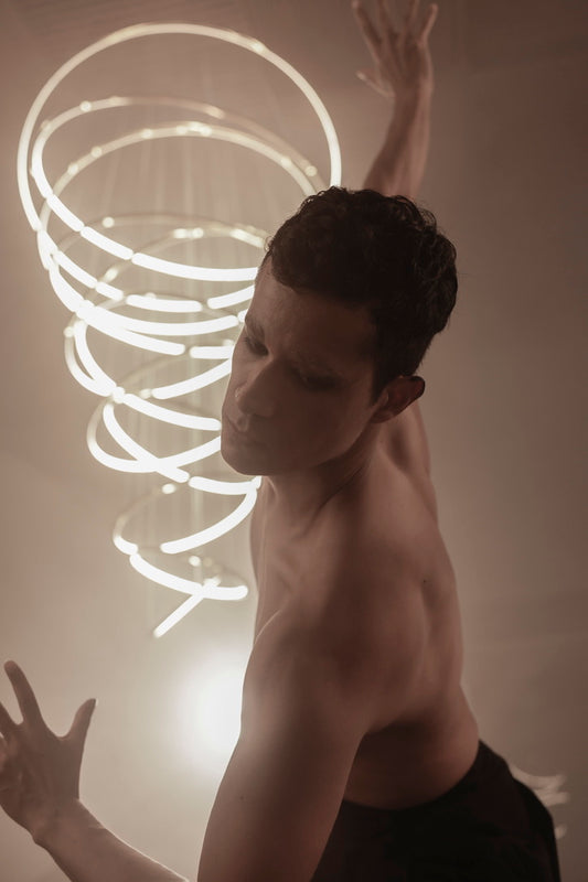 Hombre bailando frente a lámpara de espiral LED, iluminación moderna y artística