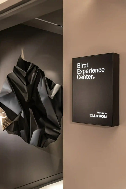 Entrada de centro de experiencia de iluminación moderna con cartel y escultura negra abstracta