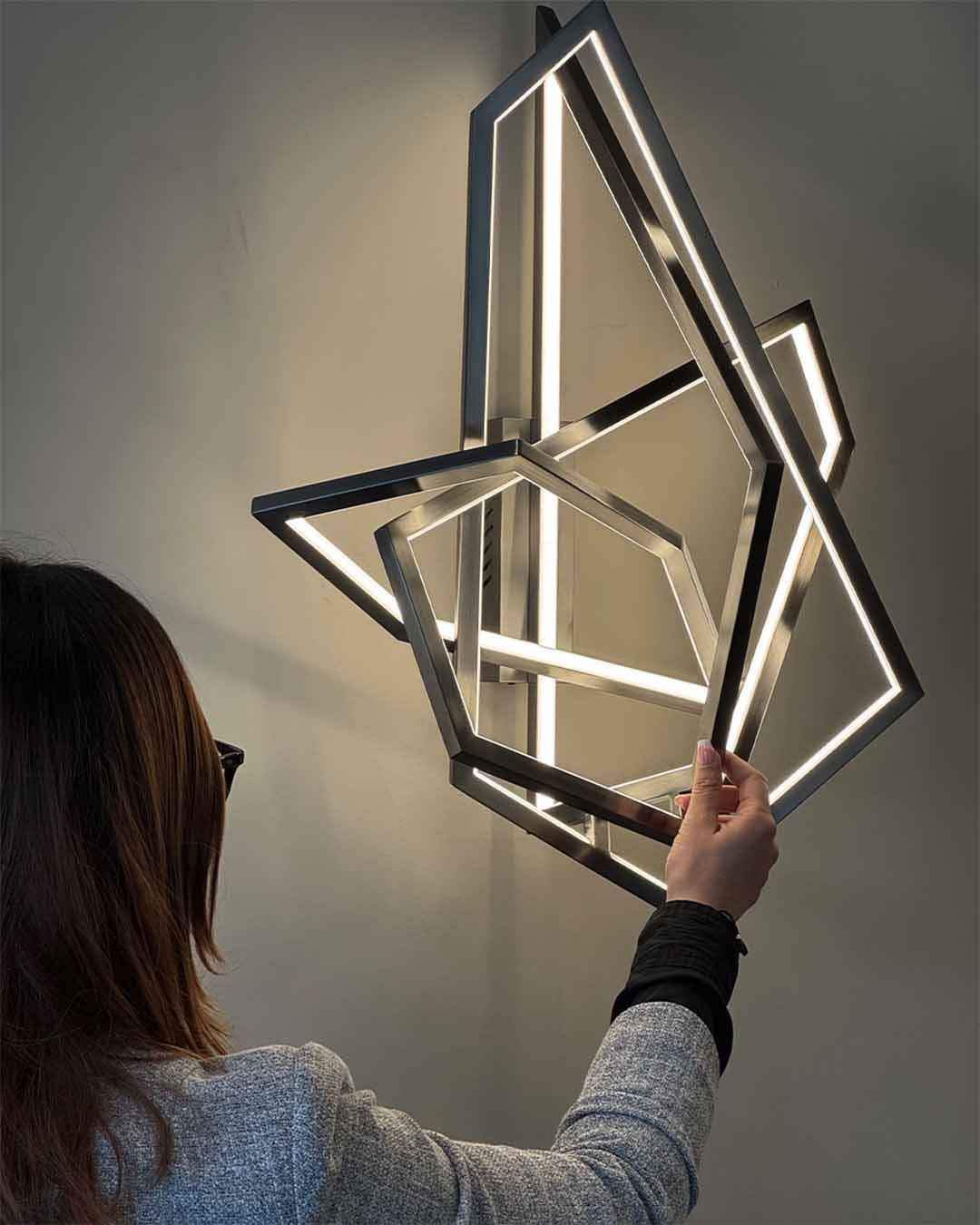 Lámpara de pared moderna geométrica encendida, mujer ajustándola, iluminación Birot MX