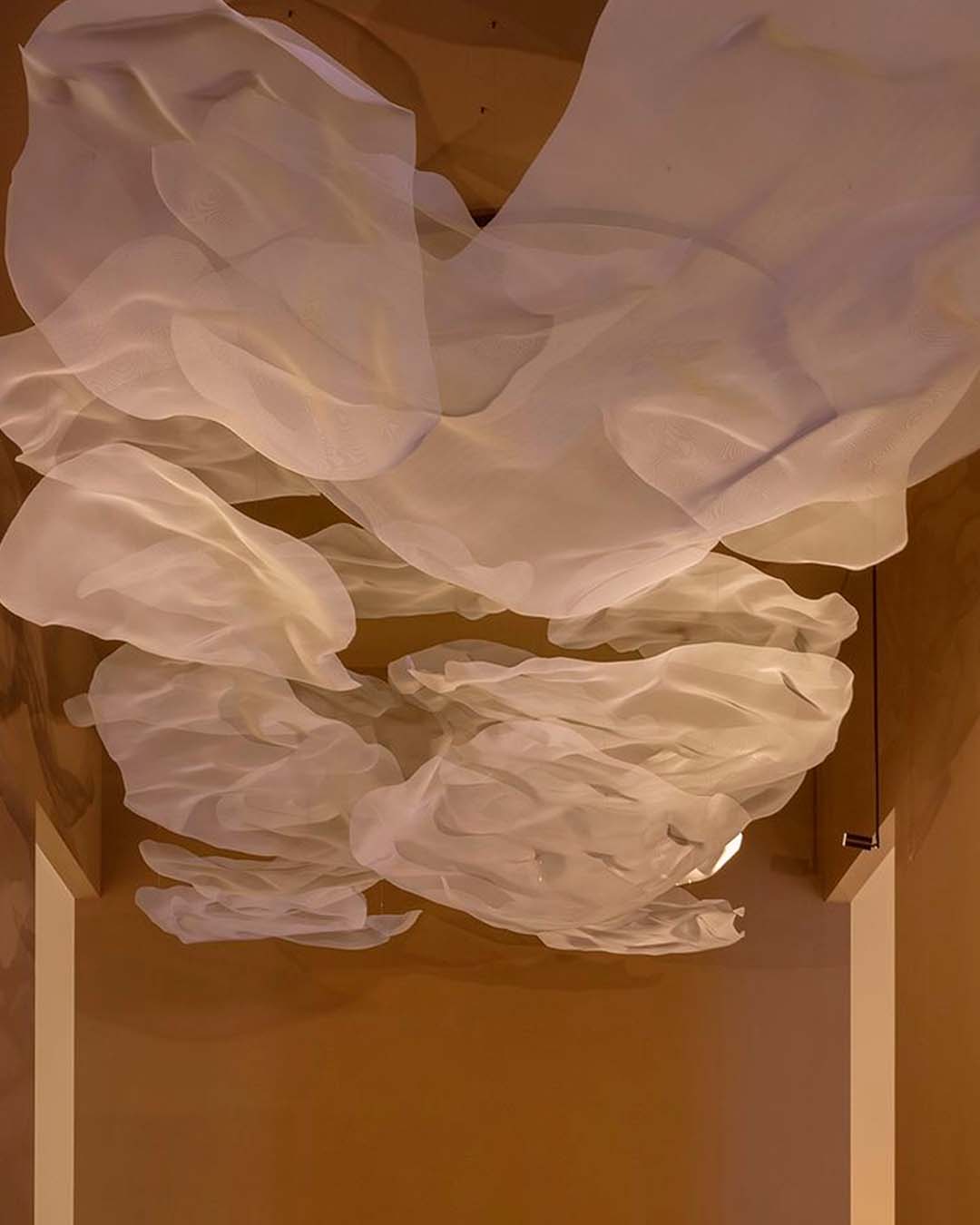 Luminaria decorativa en techo interior con formas orgánicas blancas, iluminación moderna.