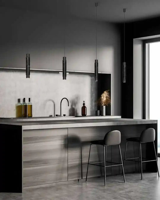 Cocina moderna con lámparas colgantes negras, barra de mármol y taburetes, iluminación boutique