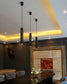 Lámparas colgantes modernas negras en comedor elegante con luces LED indirectas y decoración artística.