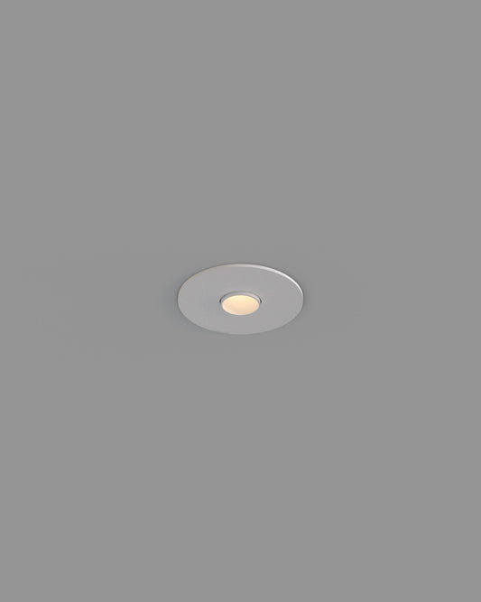 Luz empotrable de techo circular blanca, encendida, sobre fondo gris, iluminación interior.