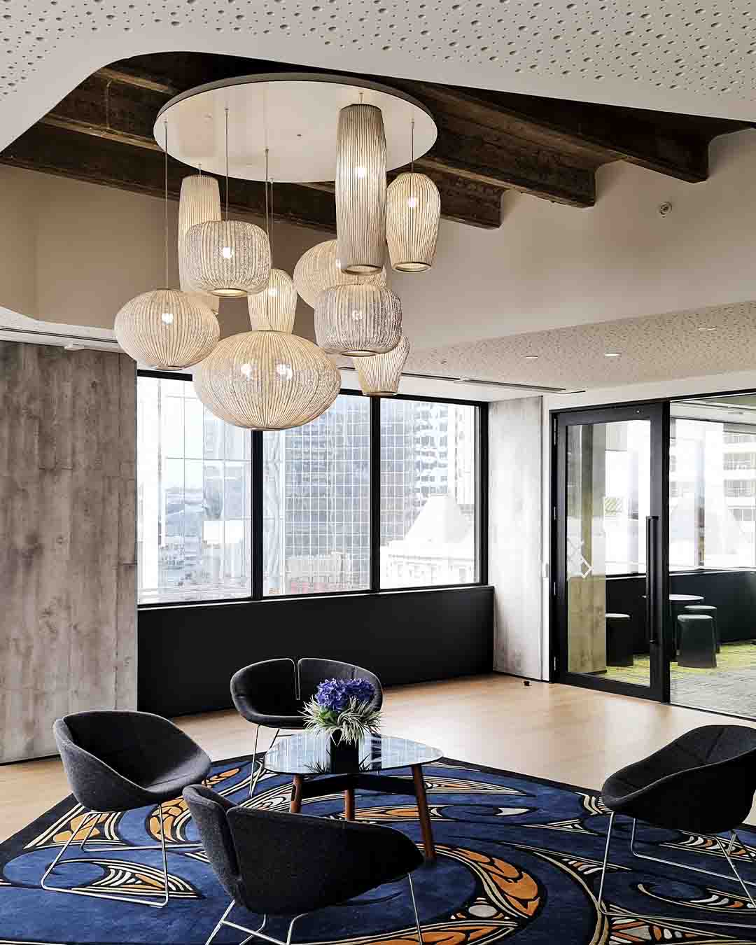 Lámparas colgantes modernas en sala de estar elegante con sillones y alfombra decorativa.