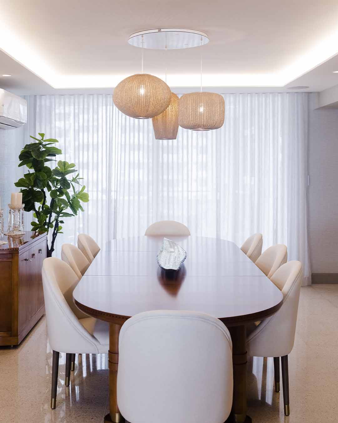 Lámparas colgantes de mimbre sobre comedor elegante con sillas blancas y mesa de madera