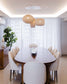 Lámparas colgantes de mimbre sobre comedor elegante con sillas blancas y mesa de madera
