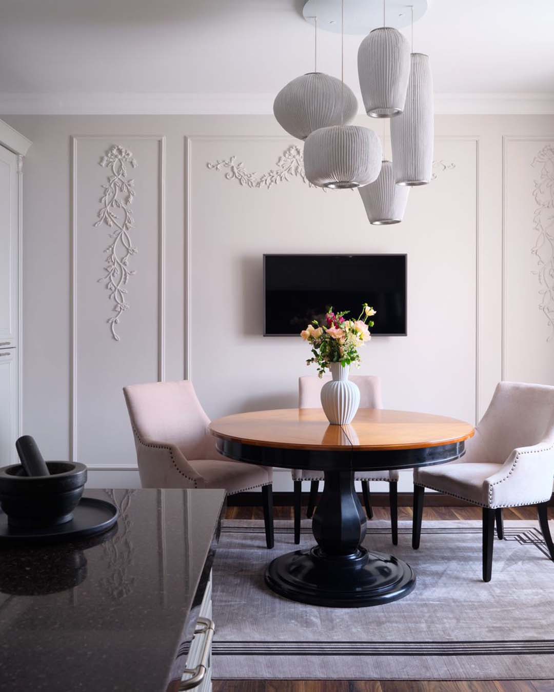 Comedor moderno con lámpara colgante de diseño, mesa redonda y sillas tapizadas, decoración elegante.