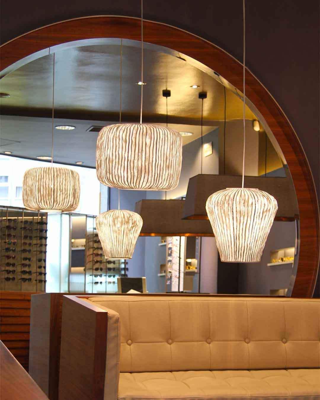 Lámparas de diseño colgantes sobre sofá beige en boutique de iluminación Birot MX