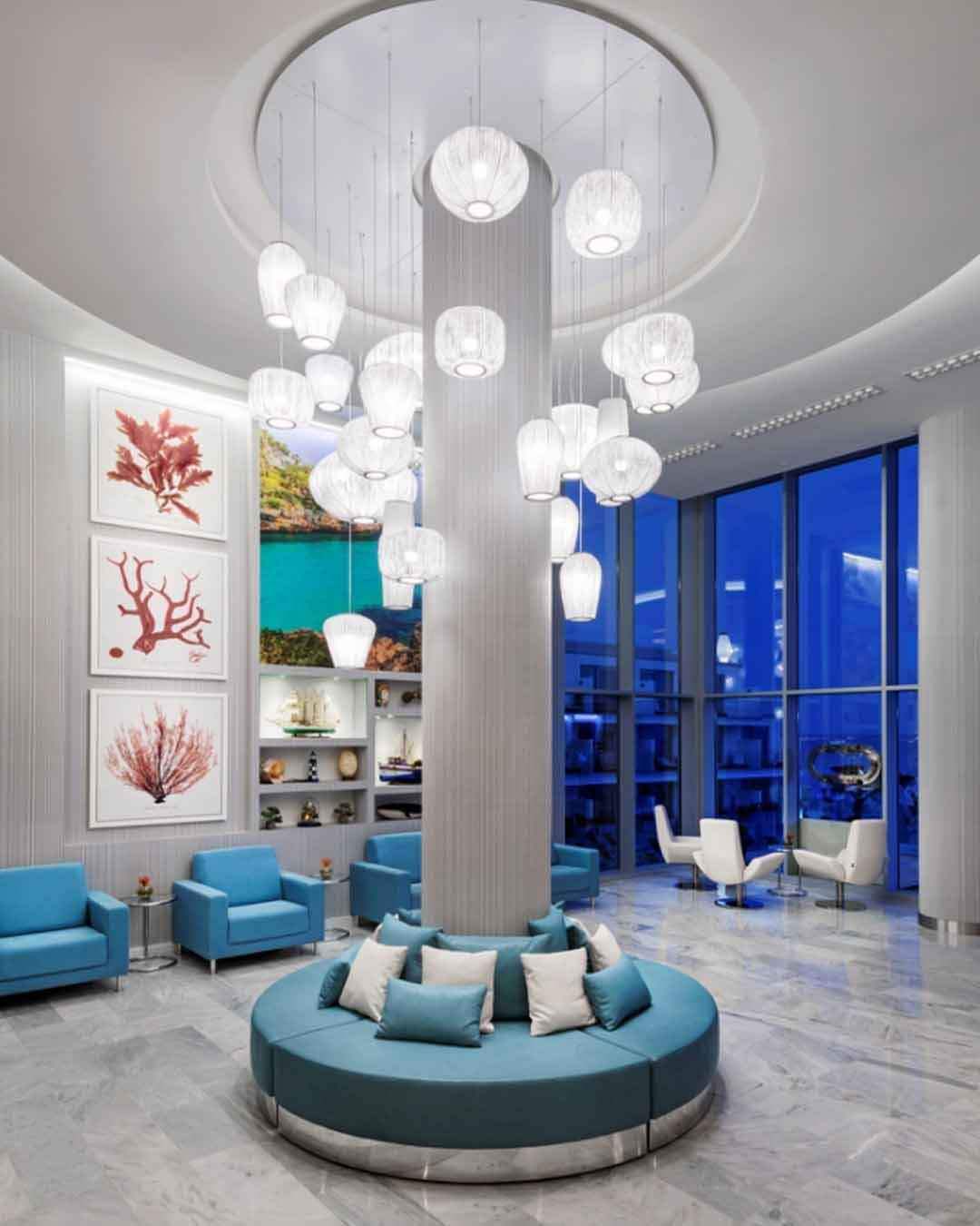 Lámparas colgantes de diseño moderno en lobby elegante con sillones azules, Birot MX iluminación.