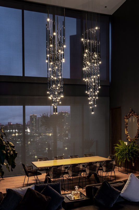 Lámparas colgantes modernas iluminando comedor elegante con ventanales grandes y mobiliario minimalista.