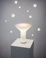 Lámpara de mesa moderna blanca en pedestal, fondo gris con detalles circulares, Birot MX iluminación.