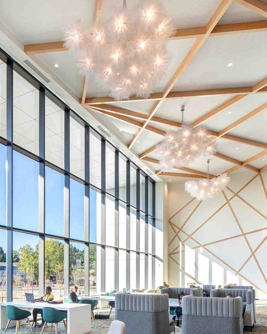 Luminarias modernas con diseño de plumas en techo de sala amplia con grandes ventanales
