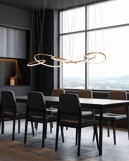 Lámpara moderna de aros dorados sobre mesa comedor en interior minimalista, Birot MX iluminación.