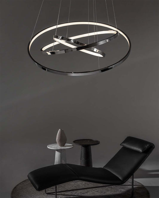 Lámpara colgante LED moderna circular en sala minimalista con sillón negro y mesas auxiliares.