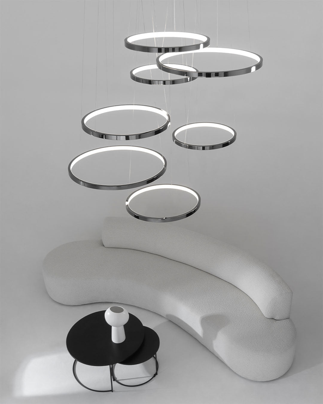 Lámpara colgante de anillos LED modernos sobre sofá curvo blanco y mesa negra en sala minimalista