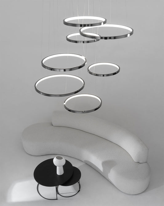 Lámpara colgante de anillos LED modernos sobre sofá curvo blanco y mesa negra en sala minimalista