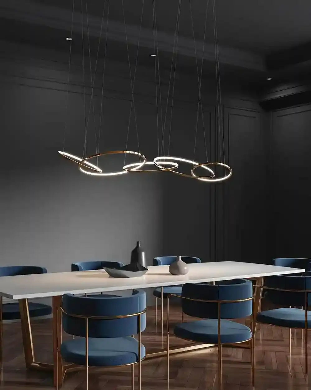 Lámpara colgante dorada moderna sobre mesa blanca y sillas azules en comedor elegante, Birot MX boutique de iluminación.