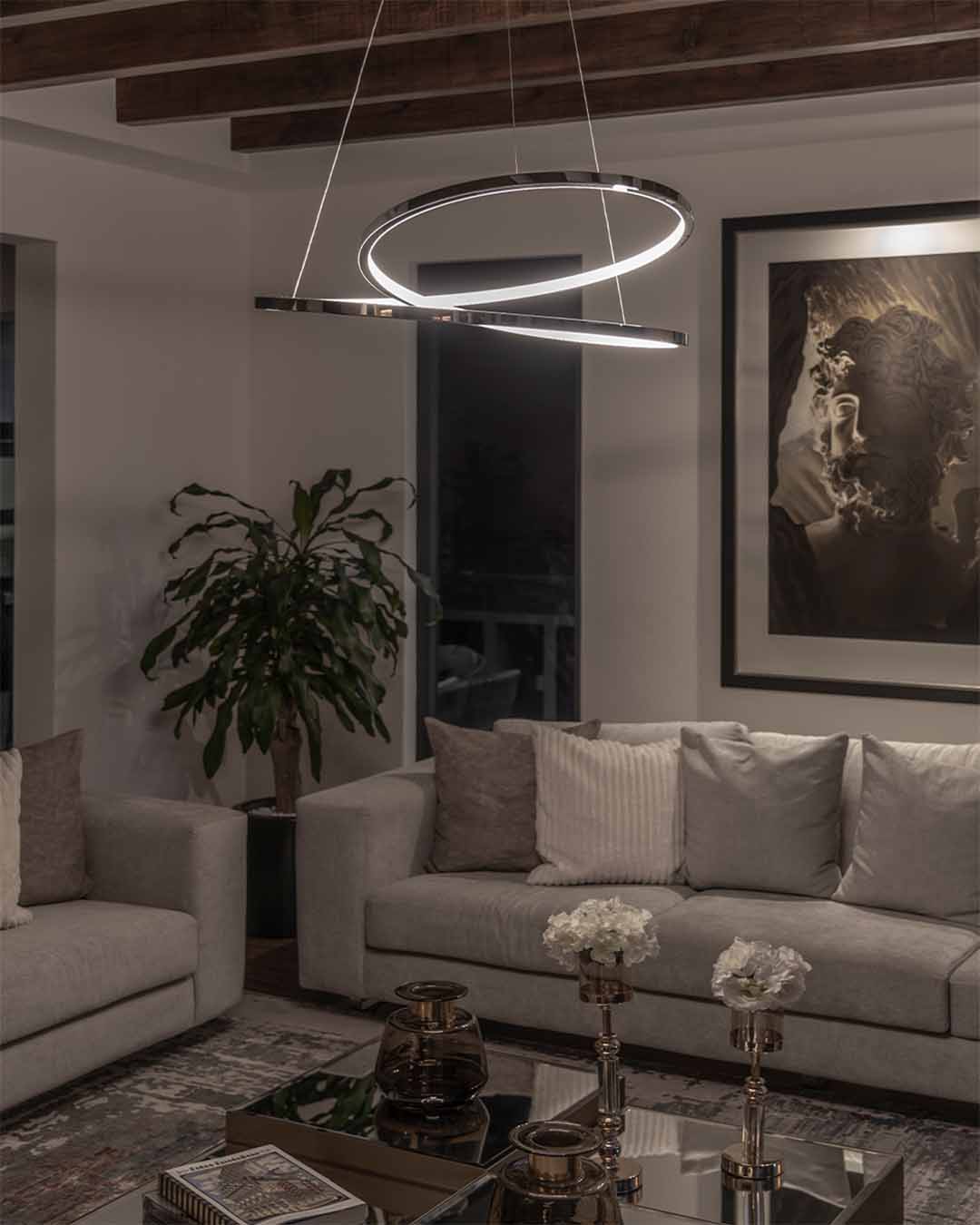 Lámpara colgante moderna circular iluminando sala elegante con sillones grises y decoración.