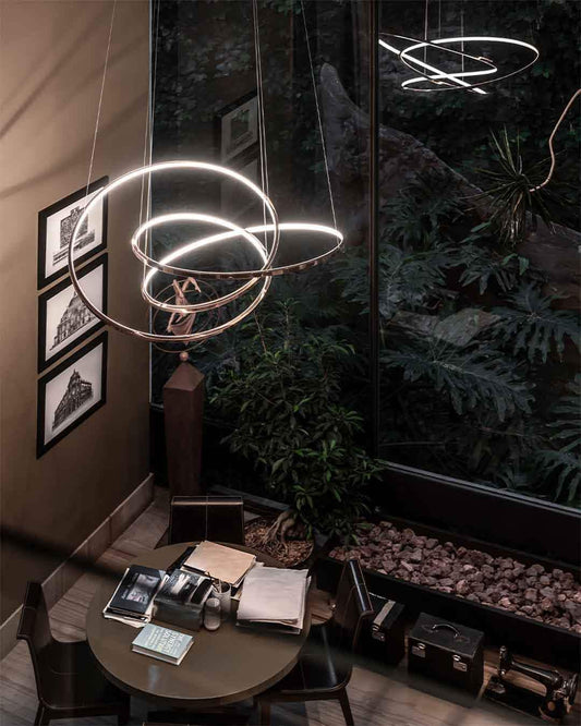 Lámpara moderna LED colgante sobre mesa de oficina junto a ventana y plantas, Birot MX iluminación.