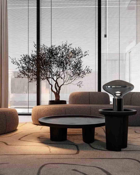 Sala moderna con mesa negra, lámpara decorativa y sillones, iluminación boutique Birot MX.