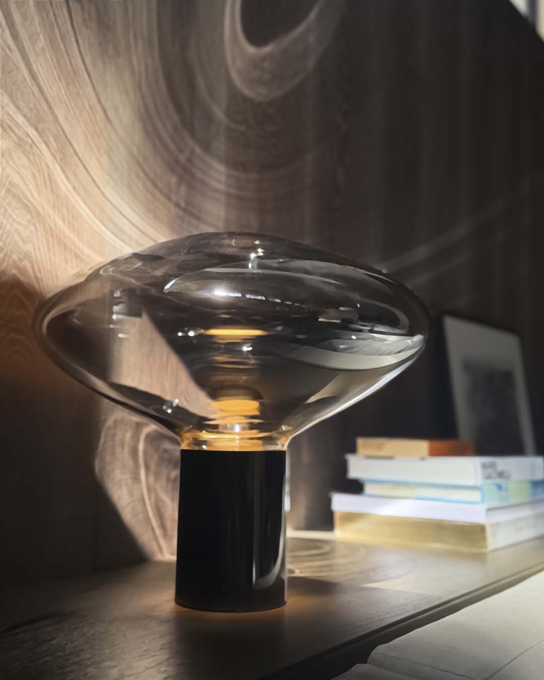Lámpara de mesa moderna Invo de vidrio soplado con base cilíndrica encendida.