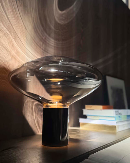 Lámpara de mesa moderna Invo de vidrio soplado con base cilíndrica encendida.