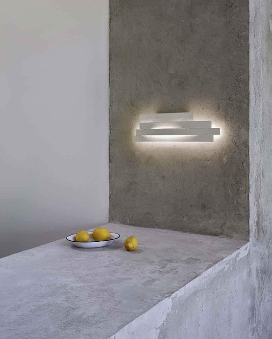 Lámpara de pared moderna encendida en ambiente minimalista con limones sobre mesa de concreto, Birot MX boutique de iluminación.