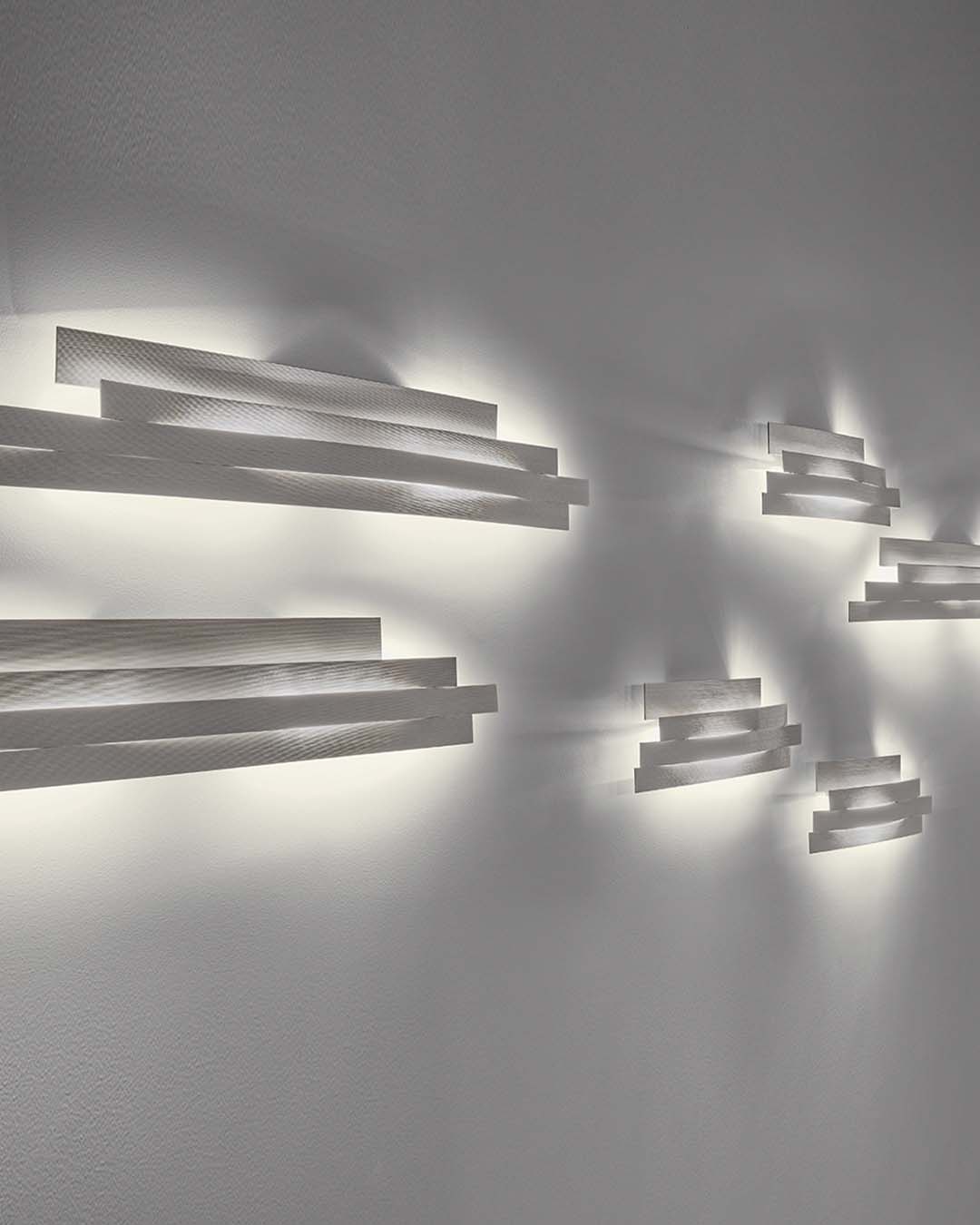 Apliques modernos de pared blancos encendidos en pared blanca, boutique de iluminación Birot MX