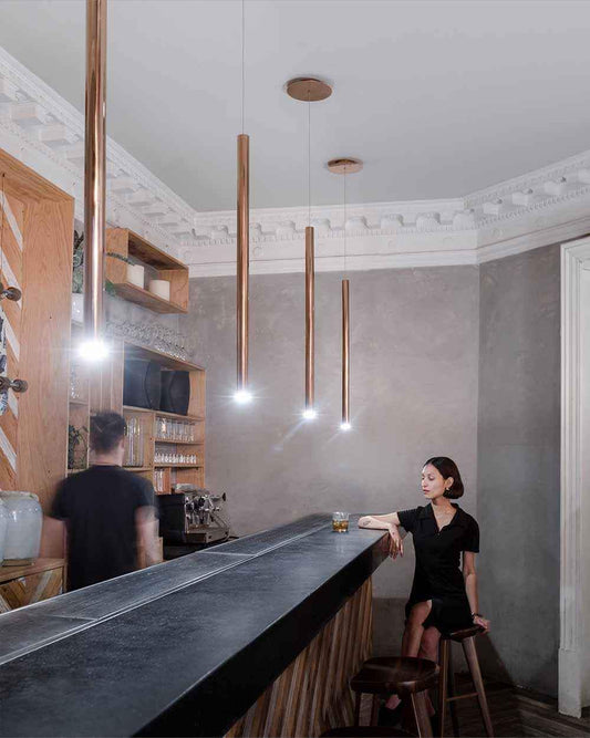 Lámparas colgantes doradas modernas en bar elegante, decoración minimalista, Birot MX iluminación.