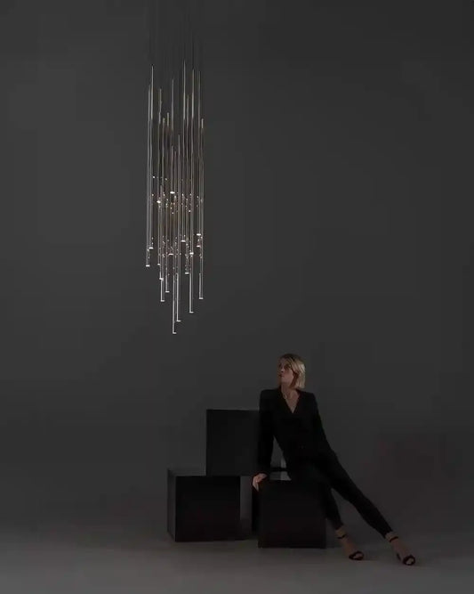 Lámpara colgante moderna Lungo en ambiente minimalista con mujer sentada, iluminación decorativa Birot MX.