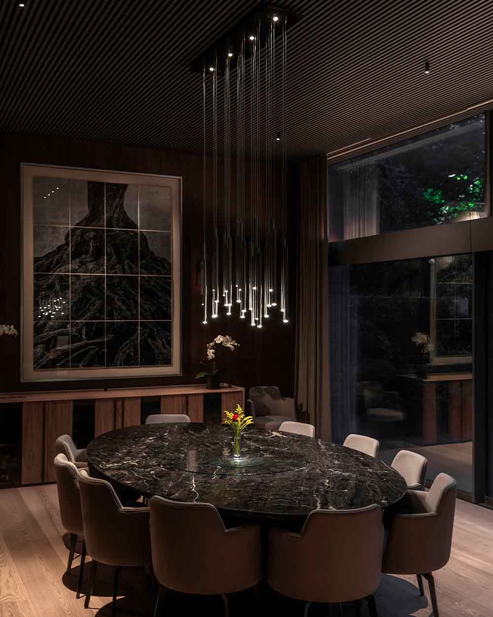 Lámpara colgante moderna sobre mesa de comedor ovalada de mármol en sala elegante.
