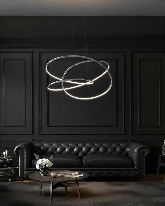 Lámpara moderna de anillos LED sobre sofá de piel negro en sala elegante, Birot MX iluminación.