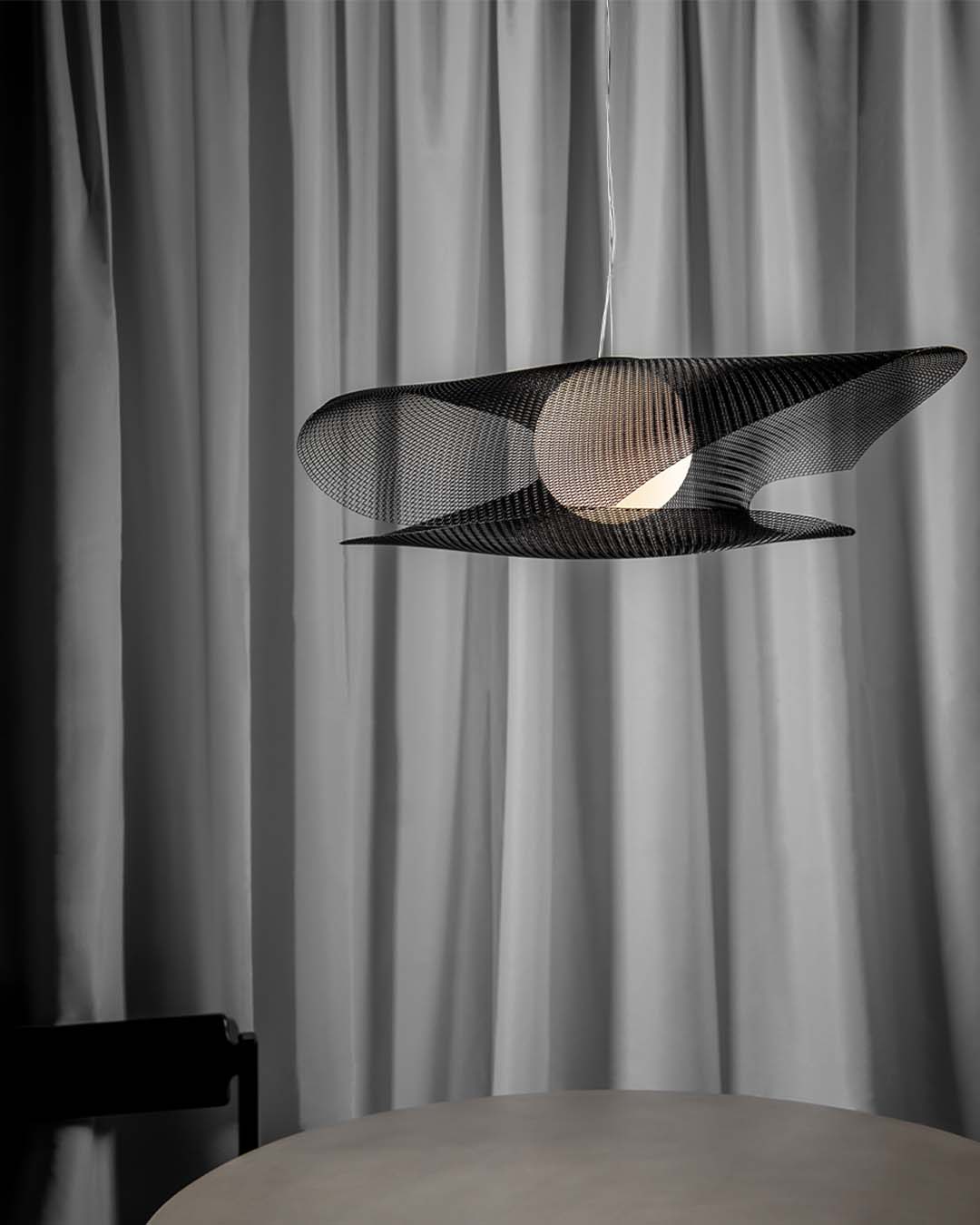 Lámpara colgante moderna negra sobre mesa, cortinas grises al fondo, iluminación Birot MX