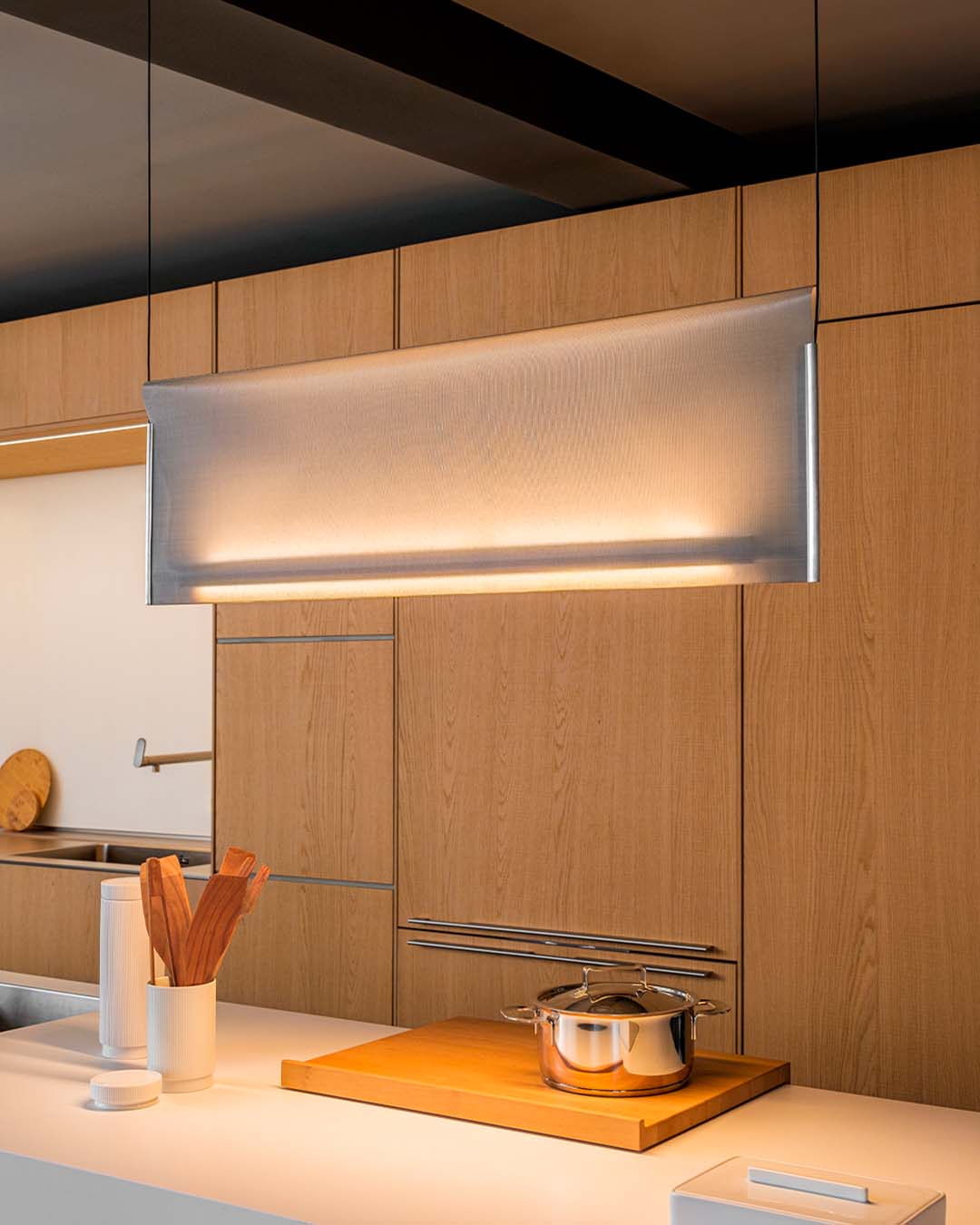 Lámpara colgante moderna iluminando cocina minimalista con muebles de madera, Birot MX