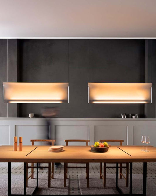 Lámparas colgantes modernas iluminando comedor con mesa de madera y decoración minimalista.