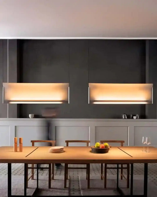Lámparas colgantes modernas iluminando comedor con mesa de madera y decoración minimalista.