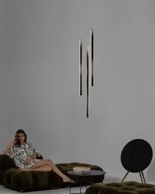 Lámpara colgante moderna negra en sala minimalista con sofá verde y mesa baja