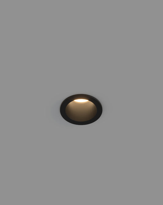 Lámpara empotrable negra de techo encendida, luz cálida, diseño minimalista.