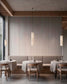 Lámpara colgante minimalista Nua en malla de acero sobre mesa de restaurante con iluminación cálida.