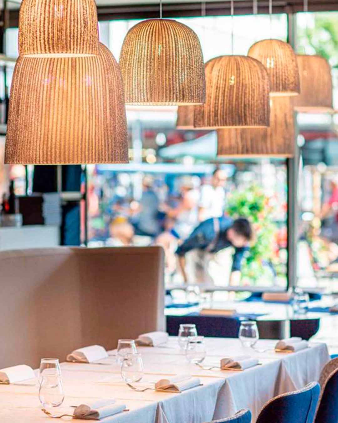 Lámparas colgantes de mimbre iluminando comedor moderno con mesa puesta